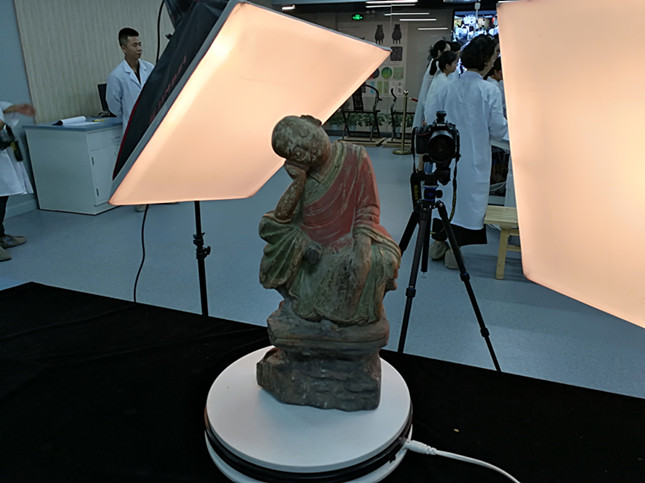 一件明代罗汉木雕随着自动转盘旋转，两台照相仪器在拍摄。韩宏摄.jpg