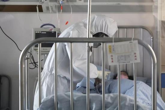 医护人员身穿防护服，进入病房为收治在此的孩子检查身体