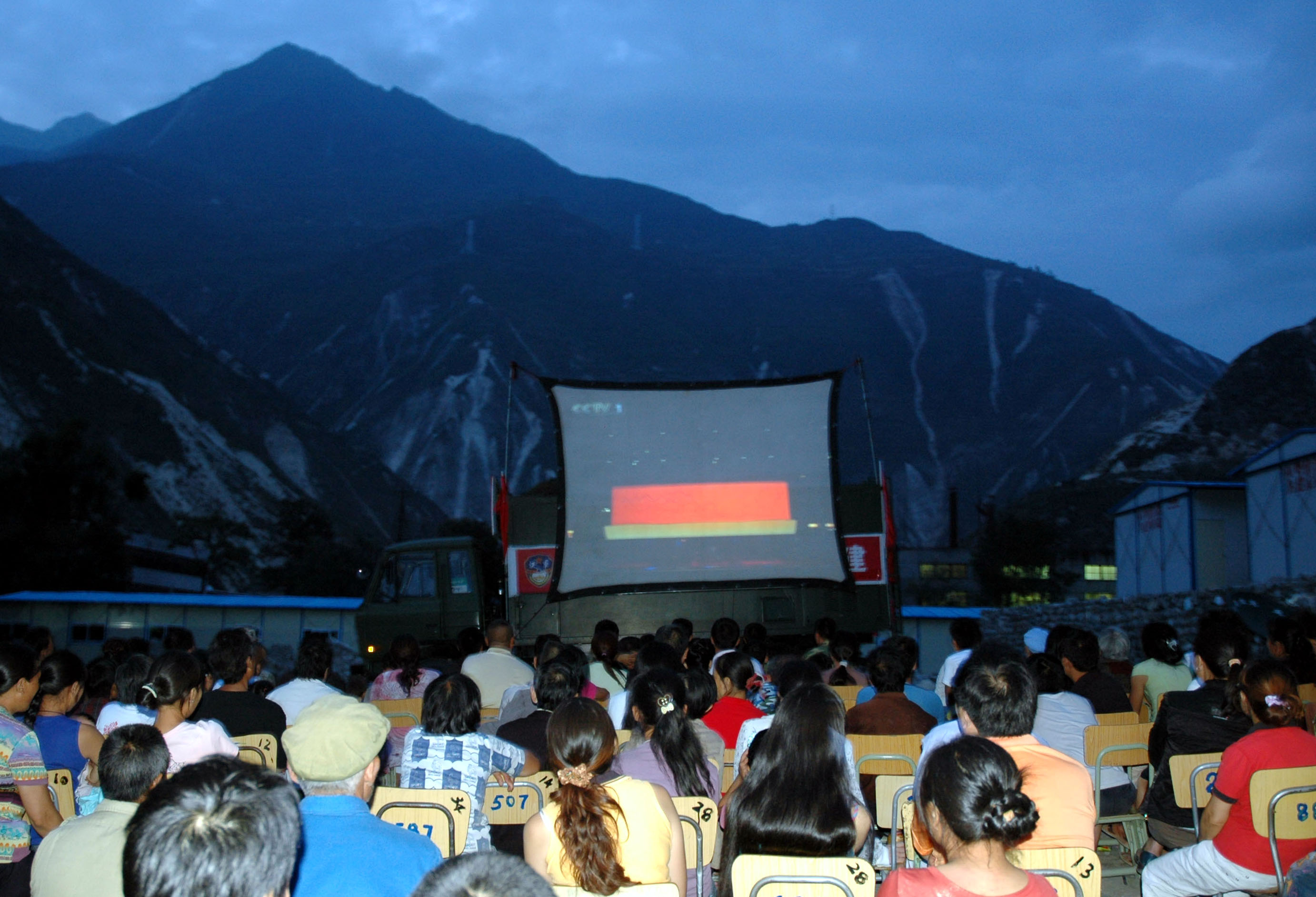 8月8日,四川汶川县七盘沟受灾群众通过大屏幕收看奥运开幕式。 当晚,济南军区红军师炮兵团将野战宣传文化放映车开到地震灾区四川省汶川县七盘沟村,让村民们通过宽大的投影屏幕观看北京奥运会开幕式。.jpg