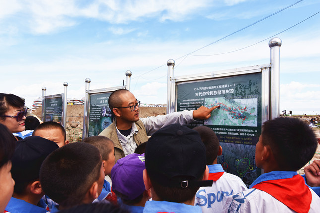 马健教授在巴里坤海子沿遗址考古发掘现场向当地小学生科普遗址情况_副本.jpg 马健教授在巴里坤海子沿遗址考古发掘现场向当地小学生科普遗址情况_副本.jpg
